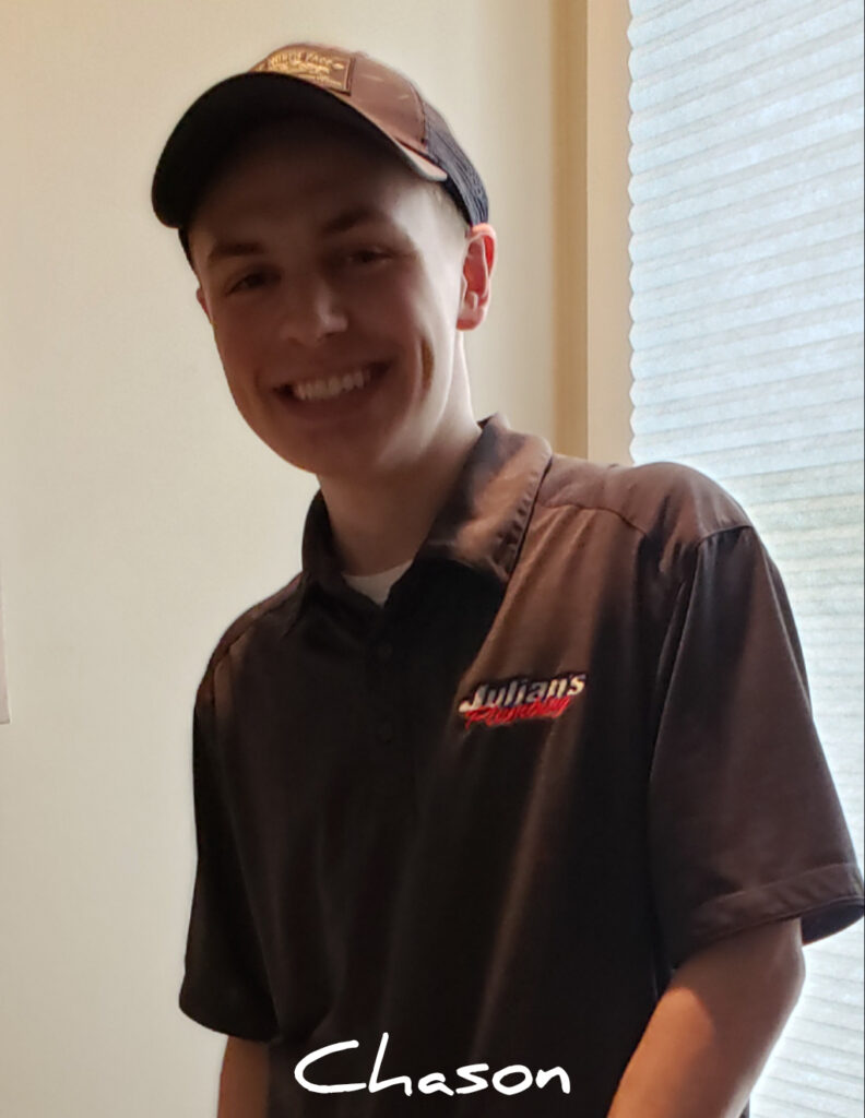 A smiling young man in a brown shirt and cap indoors