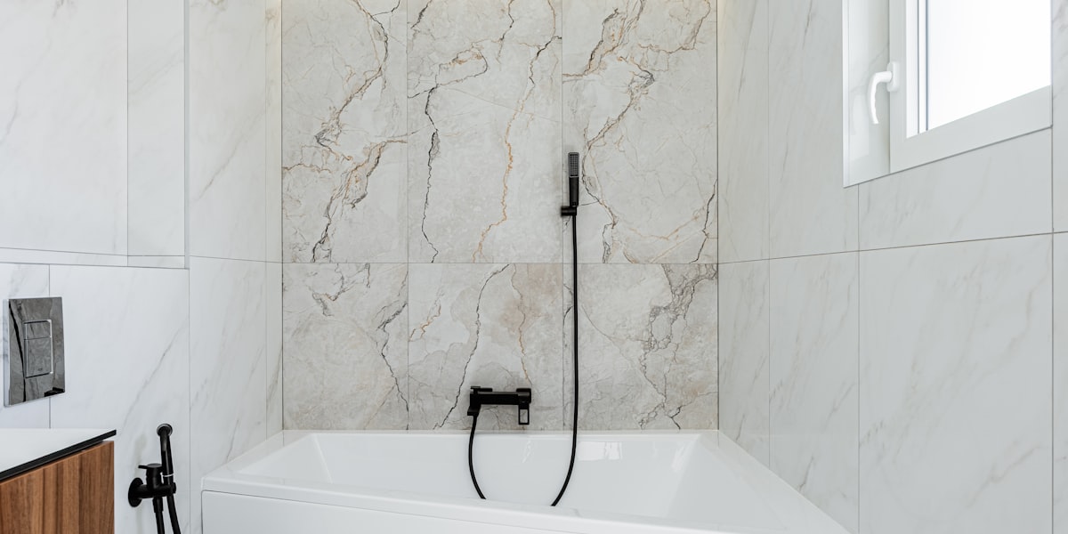 Modern marble bathroom with white bathtub and black fixtures
