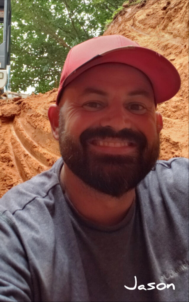 Smiling man with a beard wearing a red cap outdoors